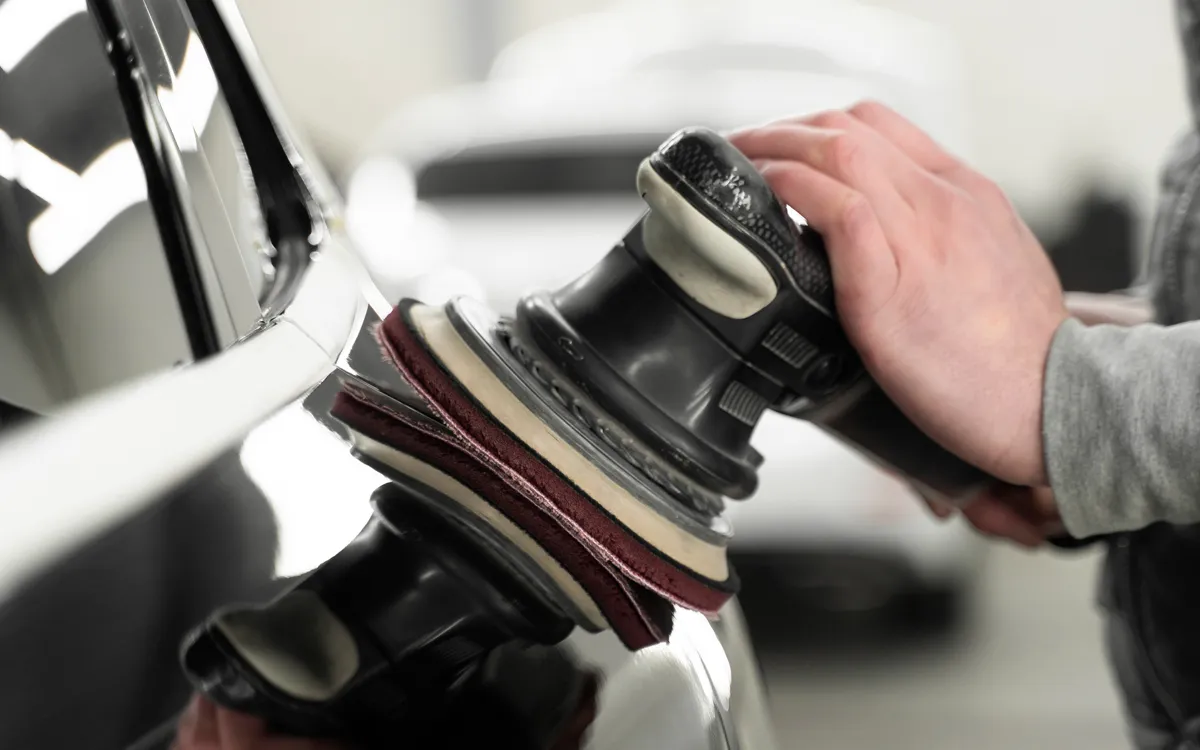 Close-up of an automobile accident claim form with two blurred toy cars in the background on a yellow surface, suggesting a collision and insurance paperwork assistance.